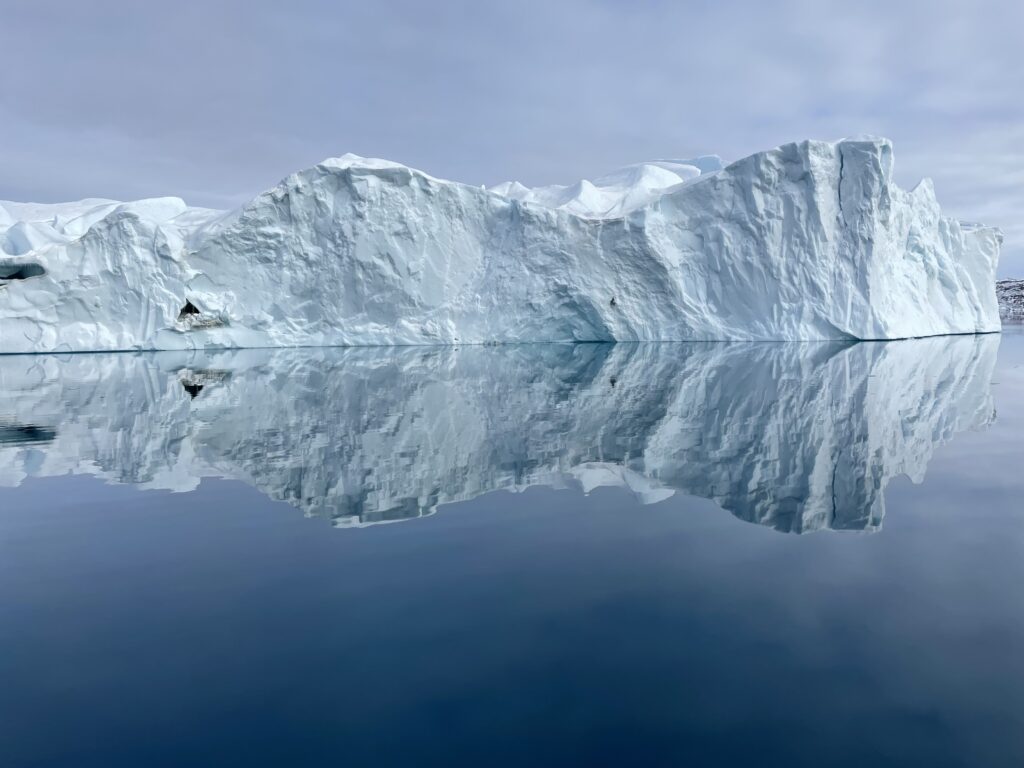 Jäävuori heijastuu peilityyneen veteen.