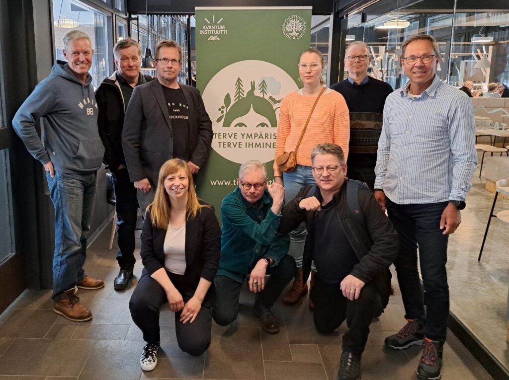 Tapathuman järjestäjät ja puhujat poseeraavat Argumentan roll-up:in edessä Vuokatin urheilukeskuksen käytävällä.