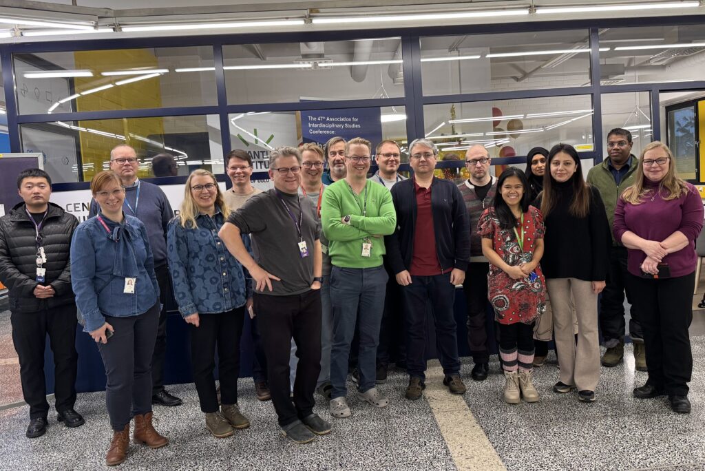 Seminaarin osallistujien ryhmäkuva MTTK:n tilan lasiseinän edustalla.